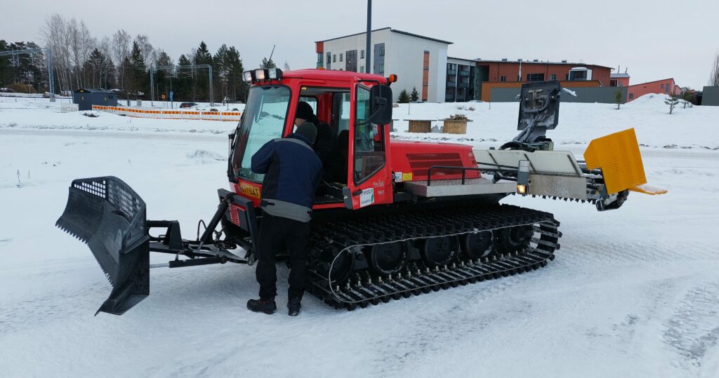 Henkilö ohjeistaa toista henkilöä latukoneen käyttöä varten.